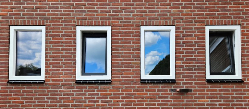 Kunstof of houten kozijnen? Wat kies jij? Bakstenen muur met vier ramen.