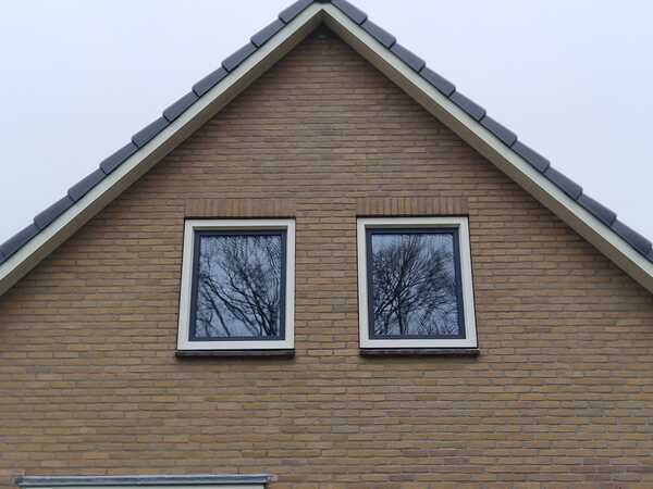 Kunststof kozijnen plaatsen in Hoogeveen met twee witte raamkozijnen onder een puntdak.