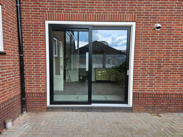 Kunststof kozijnen plaatsen in Zuidwolde voor meer licht en een open verbinding met je tuin Kunststof kozijnen plaatsen in Zuidwolde met een antraciet schuifpui en witte buitenrand.